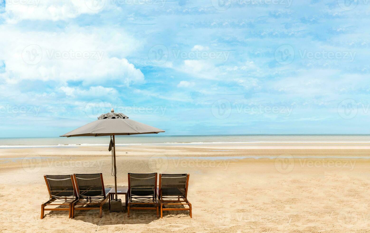 A portrait of a pair of beach seats with an umbrella on a seashore photo