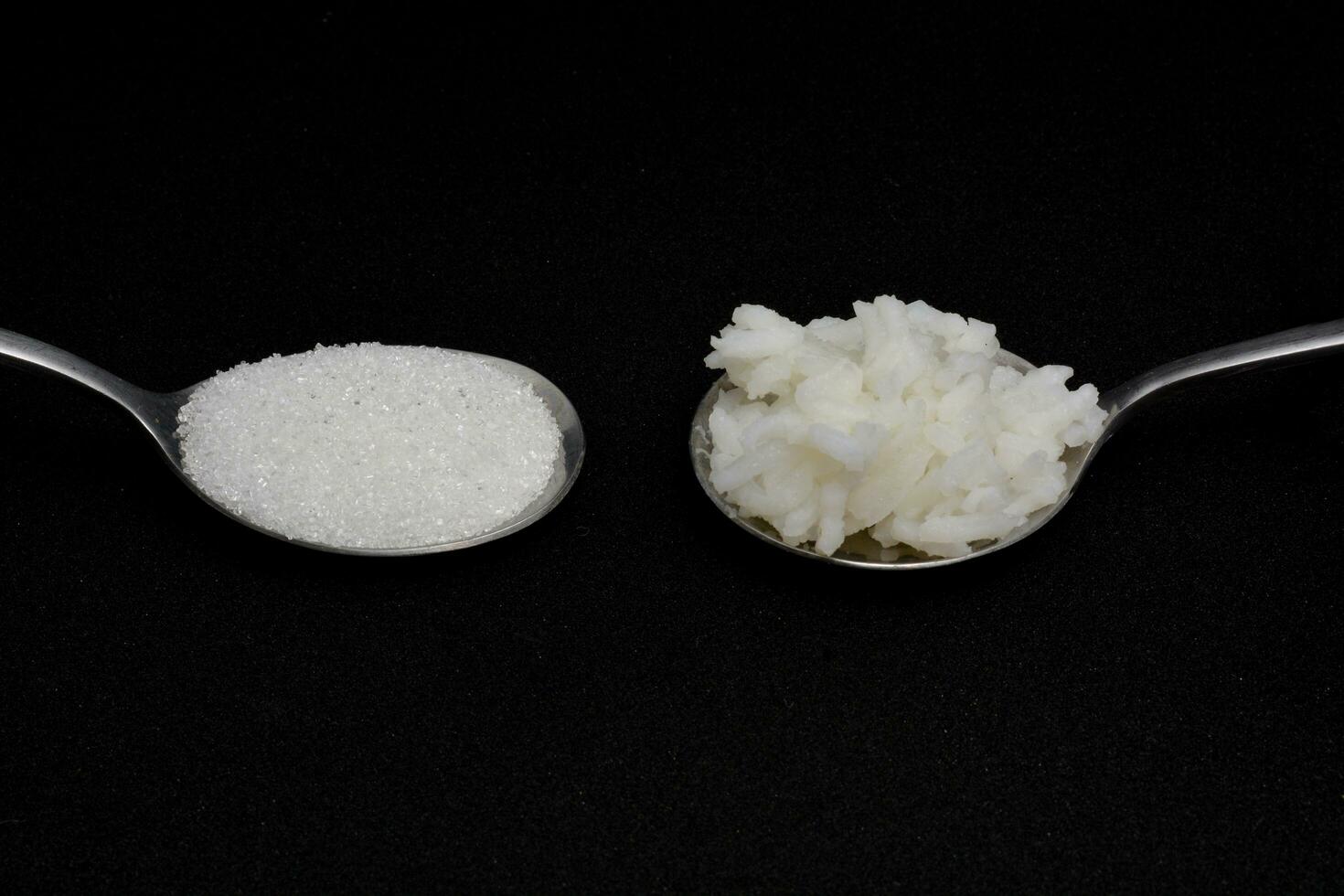 1 spoon of rice and 1 spoon of sugar Same amount of calories each day, two spoons, isolate black background photo