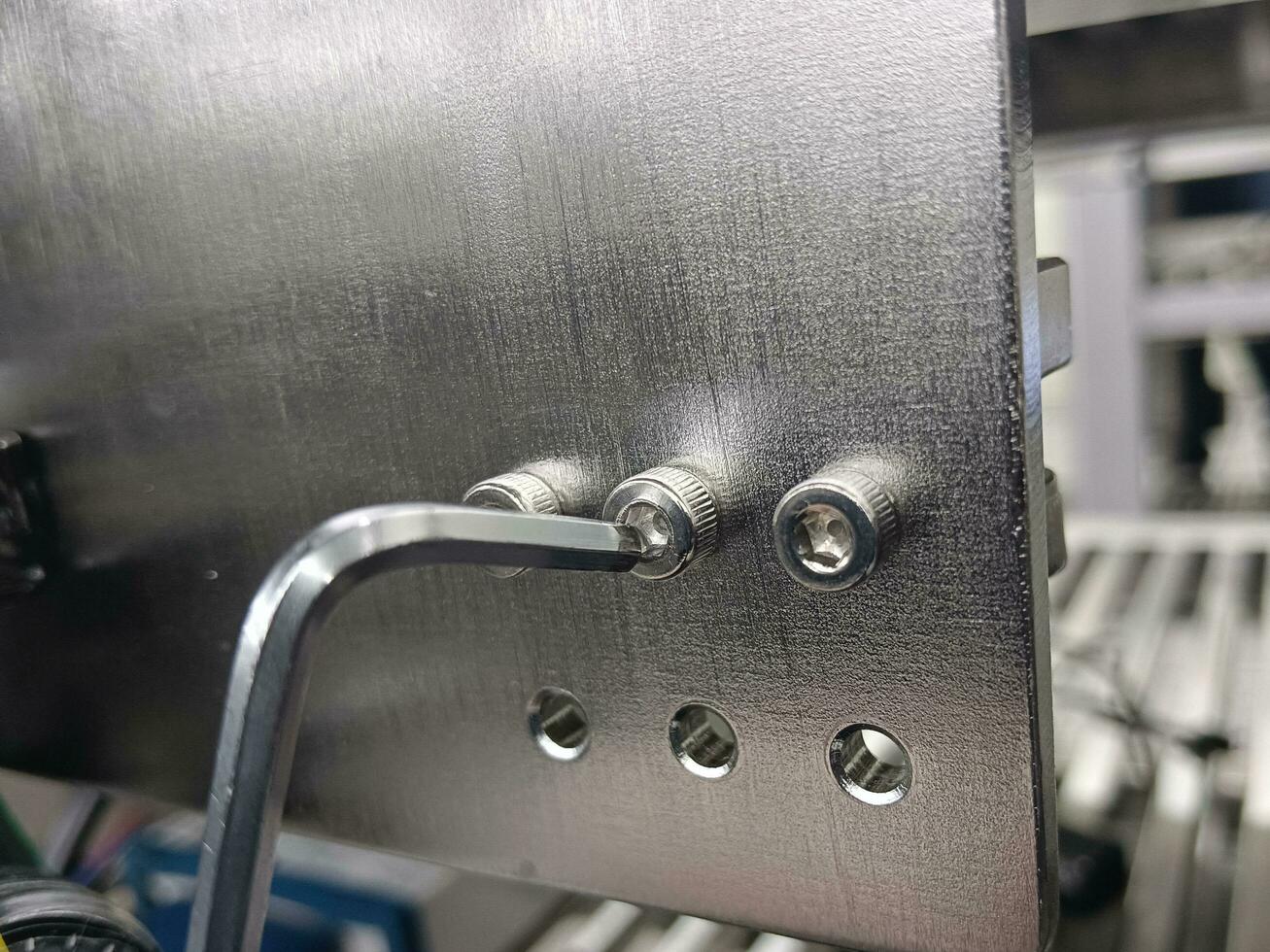 Hex wrench is unscrewing a nut made of stainless steel photo