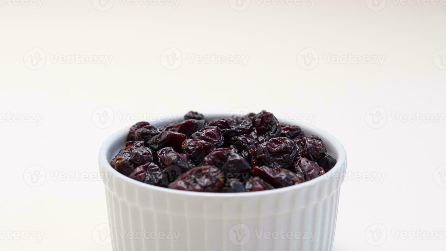 Closeup Superfood Heap Of Dried Cranberries In White Bowl On Beige Background. Selective Focus. Sweet Dehydrated Cranberries. Nutrients And Vitamins. Horizontal Plane. photo