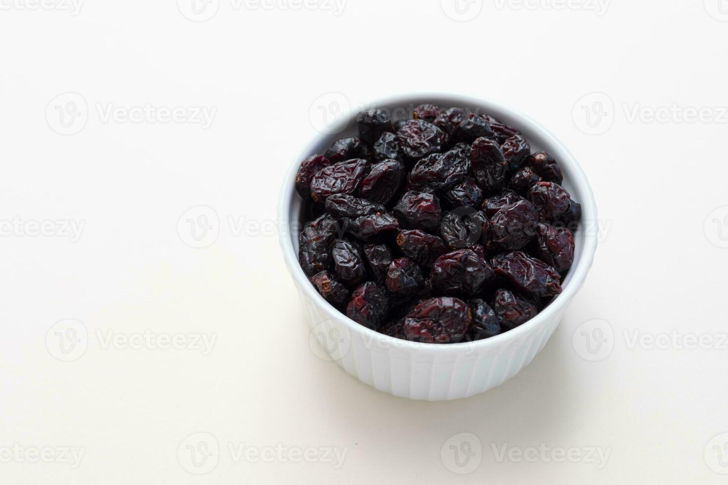 Superfood Heap Of Dried Cranberries In White Bowl On Beige Background. Selective Focus. Sweet Dehydrated Cranberries. Nutrients And Vitamins. Horizontal And Copy Space. photo