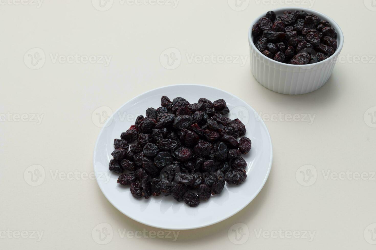 Dried Cranberries On White Plate On Beige Background. Superfood. Selective Focus. Sweet Dehydrated Cranberries. Nutrients And Vitamins. Horizontal Plane. photo