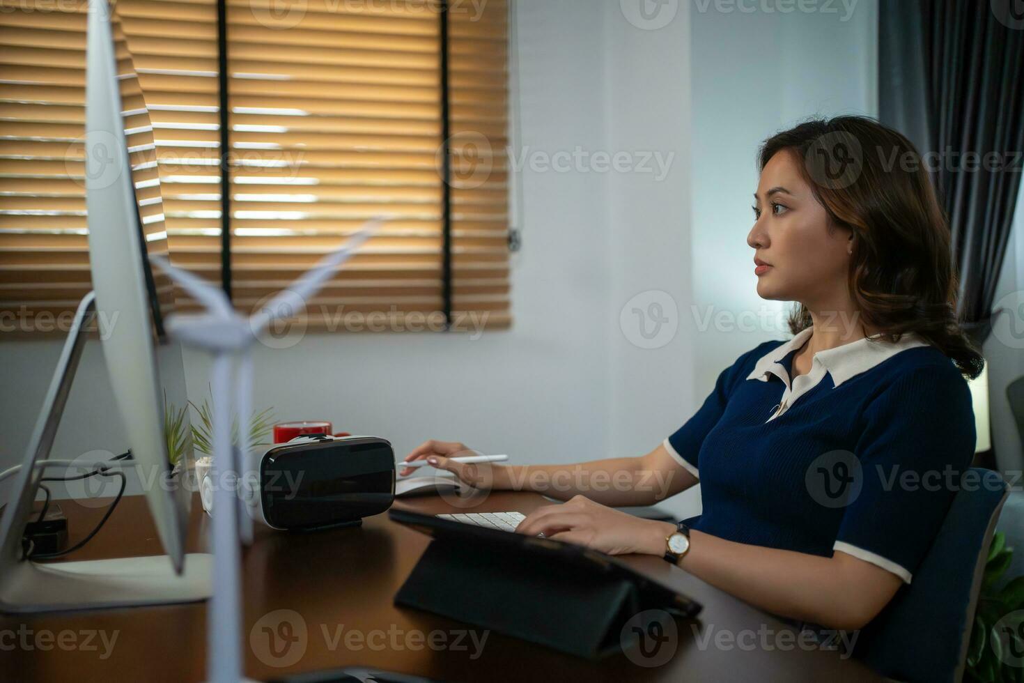 Futuristic women Engineer working with Holographic Augmented Reality and 3D Wind Turbine Model on tablet at home office ,Concept of technology and environment photo