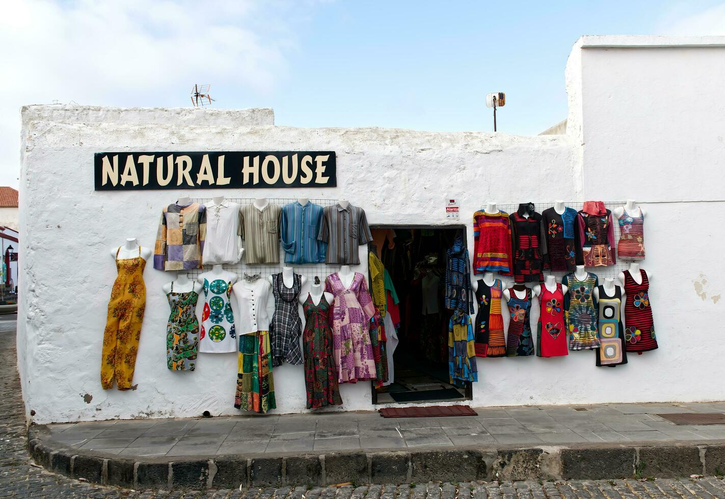 Lanzarote, Canary Islands, Spain, May 22, 2022 View on shop with clothes hanging at white wall in Teguise. photo