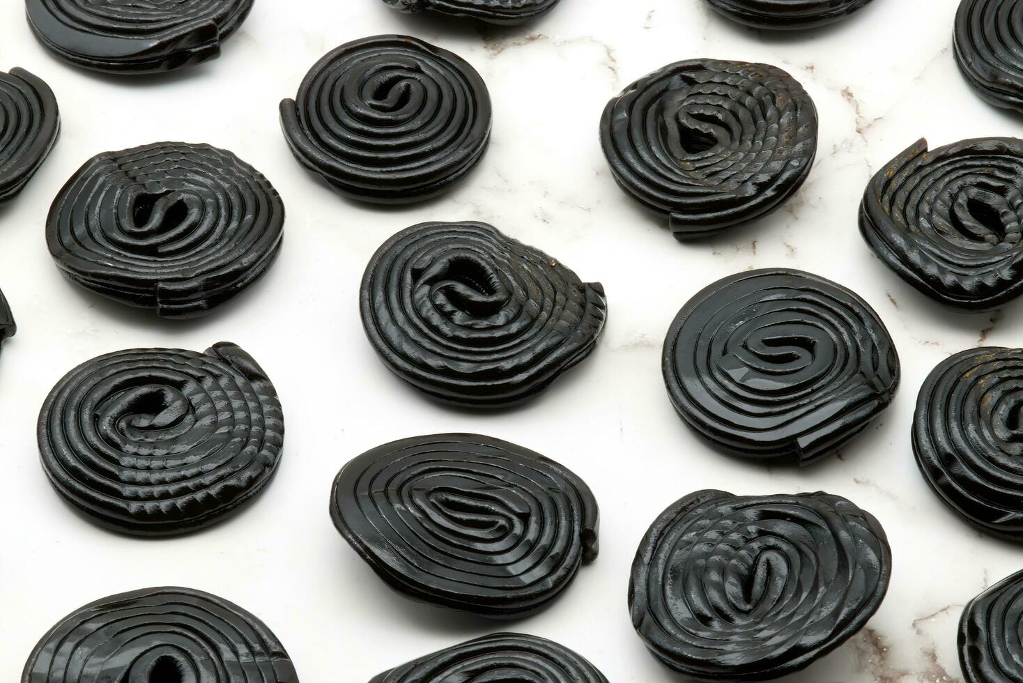 Tasty black licorice candies on white marble background photo