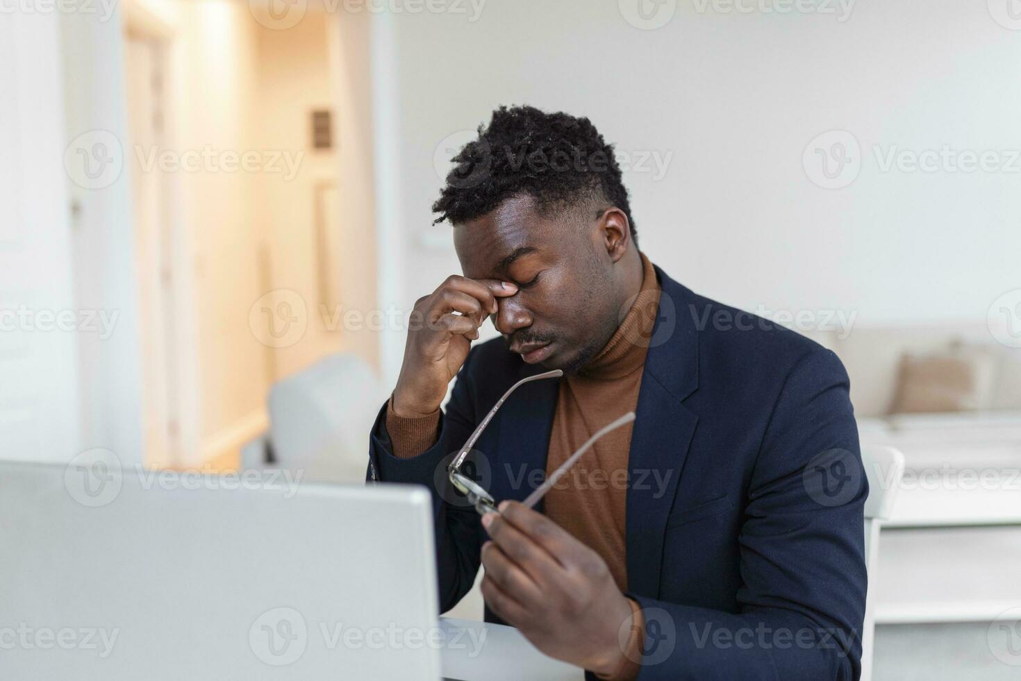 Stressed tired African American man touching temples, suffering from headache after long hours work, overworked overwhelmed businessman sitting at desk, feeling unwell photo