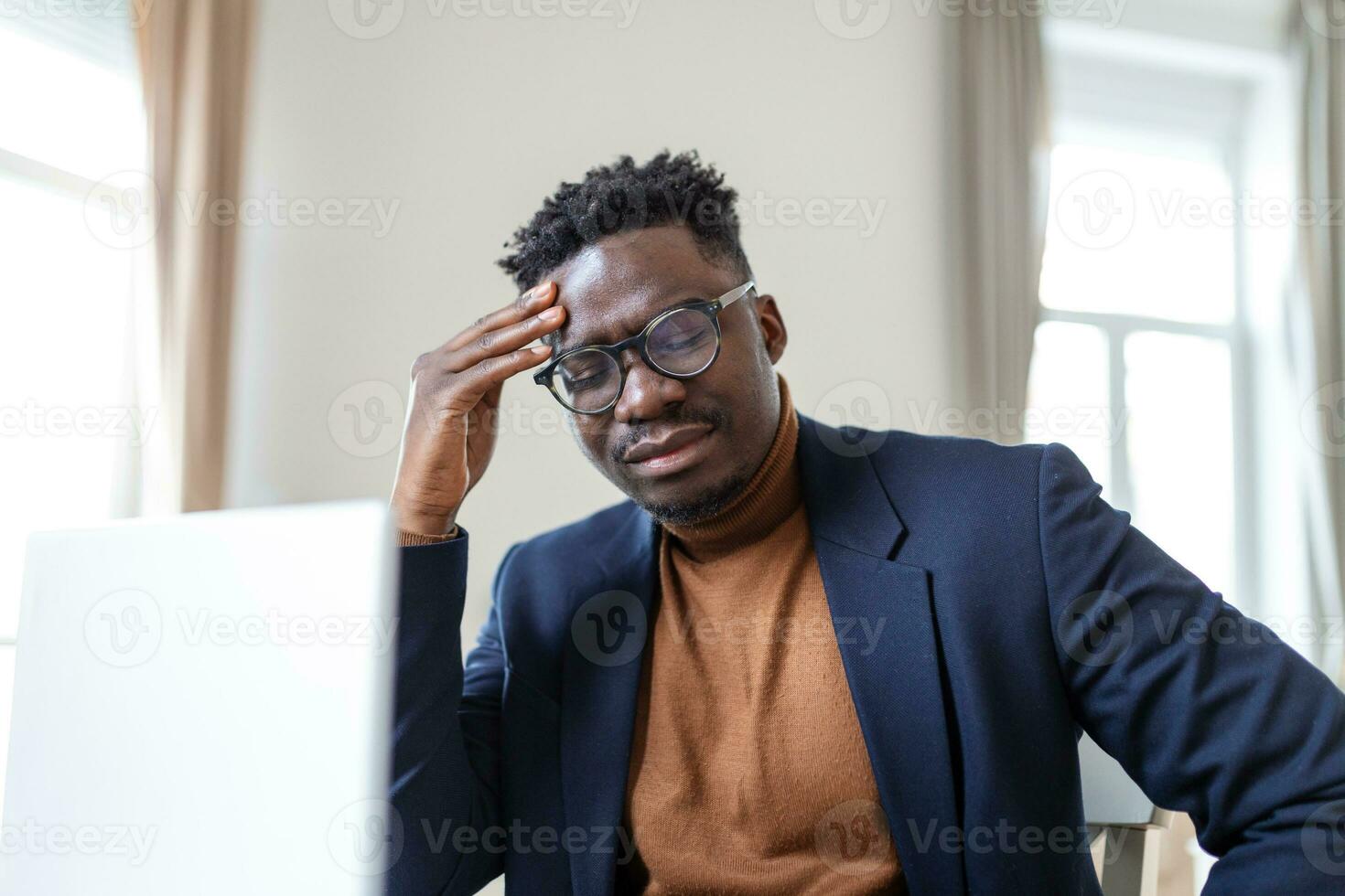 Stressed tired African American man touching temples, suffering from headache after long hours work, overworked overwhelmed businessman sitting at desk, feeling unwell photo