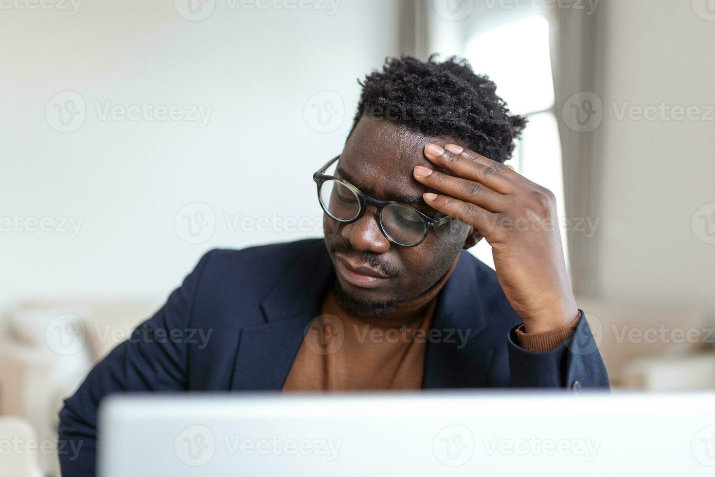 Stressed tired African American man touching temples, suffering from headache after long hours work, overworked overwhelmed businessman sitting at desk, feeling unwell photo