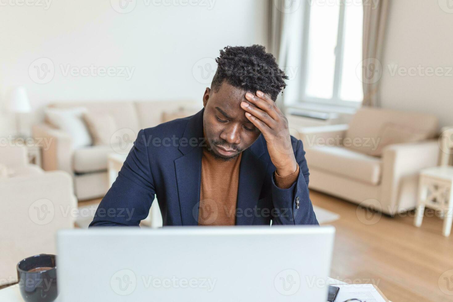 Stressed tired African American man touching temples, suffering from headache after long hours work, overworked overwhelmed businessman sitting at desk, feeling unwell photo