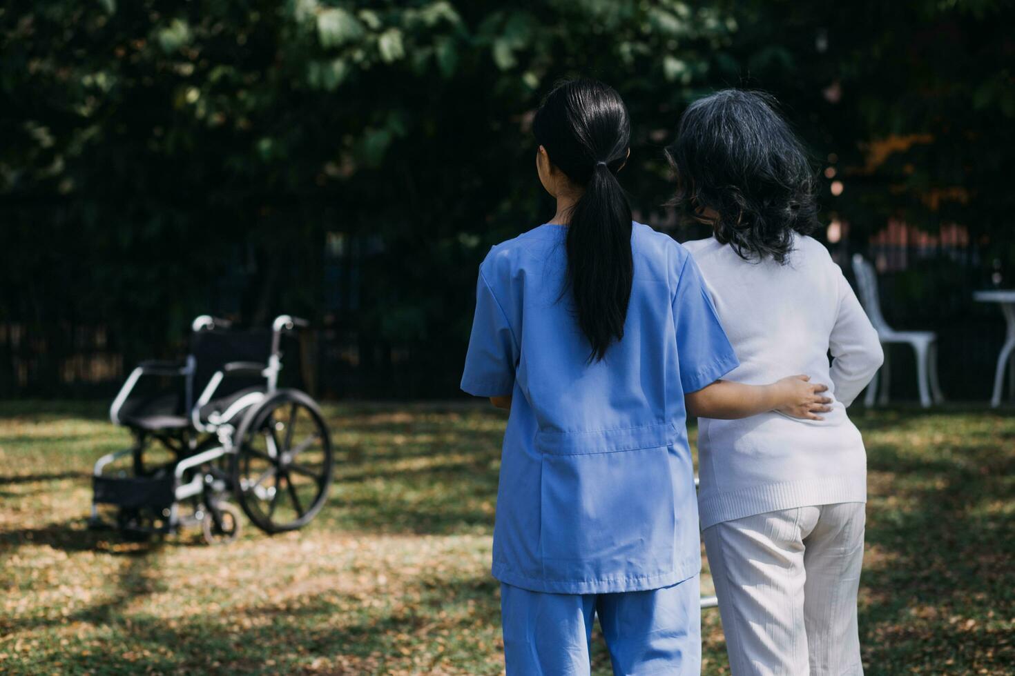 young asian physical therapist working with senior woman on walking with a walker photo