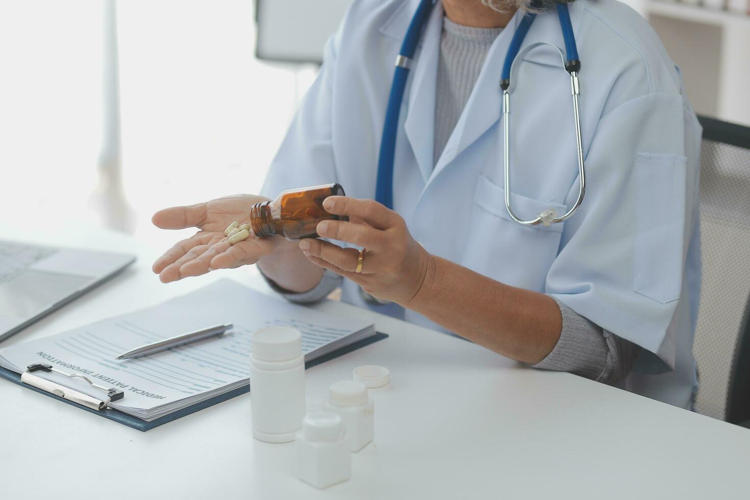 Doctor giving hope. Close up shot of young female physician leaning forward to smiling elderly lady patient holding her hand in palms. Woman caretaker in white coat supporting encouraging old person photo