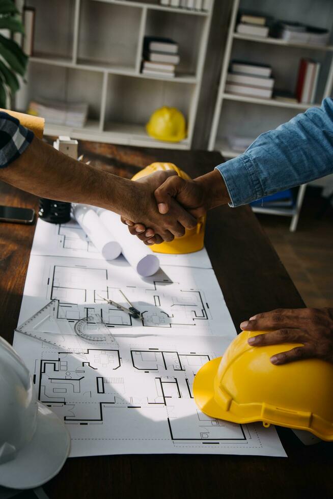 reunión de trabajo en equipo de ingenieros, trabajo de dibujo en la reunión de planos para el trabajo del proyecto con un socio en la construcción de modelos y herramientas de ingeniería en el concepto de sitio de trabajo, construcción y estructura. foto