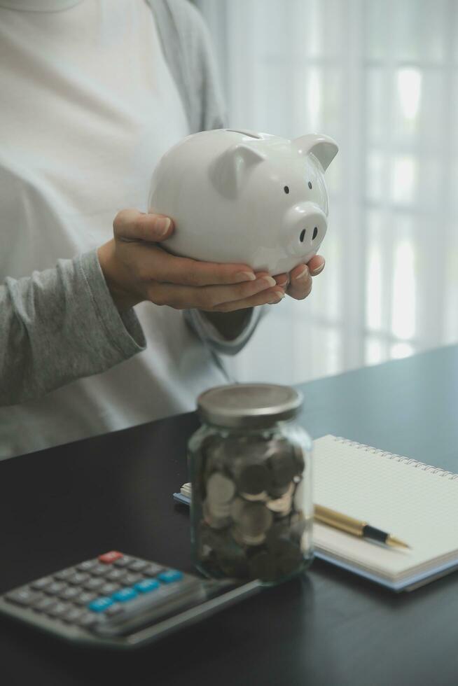 mujer mano poniendo dinero moneda dentro cerdito para ahorro dinero riqueza y financiero concepto. foto