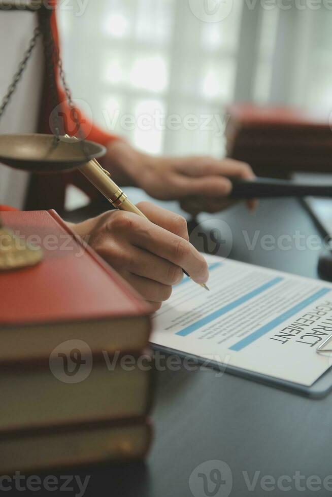 Justice and Law concept. Legal counsel presents to the client a signed contract with gavel and legal law or legal having team meeting at law firm in background photo
