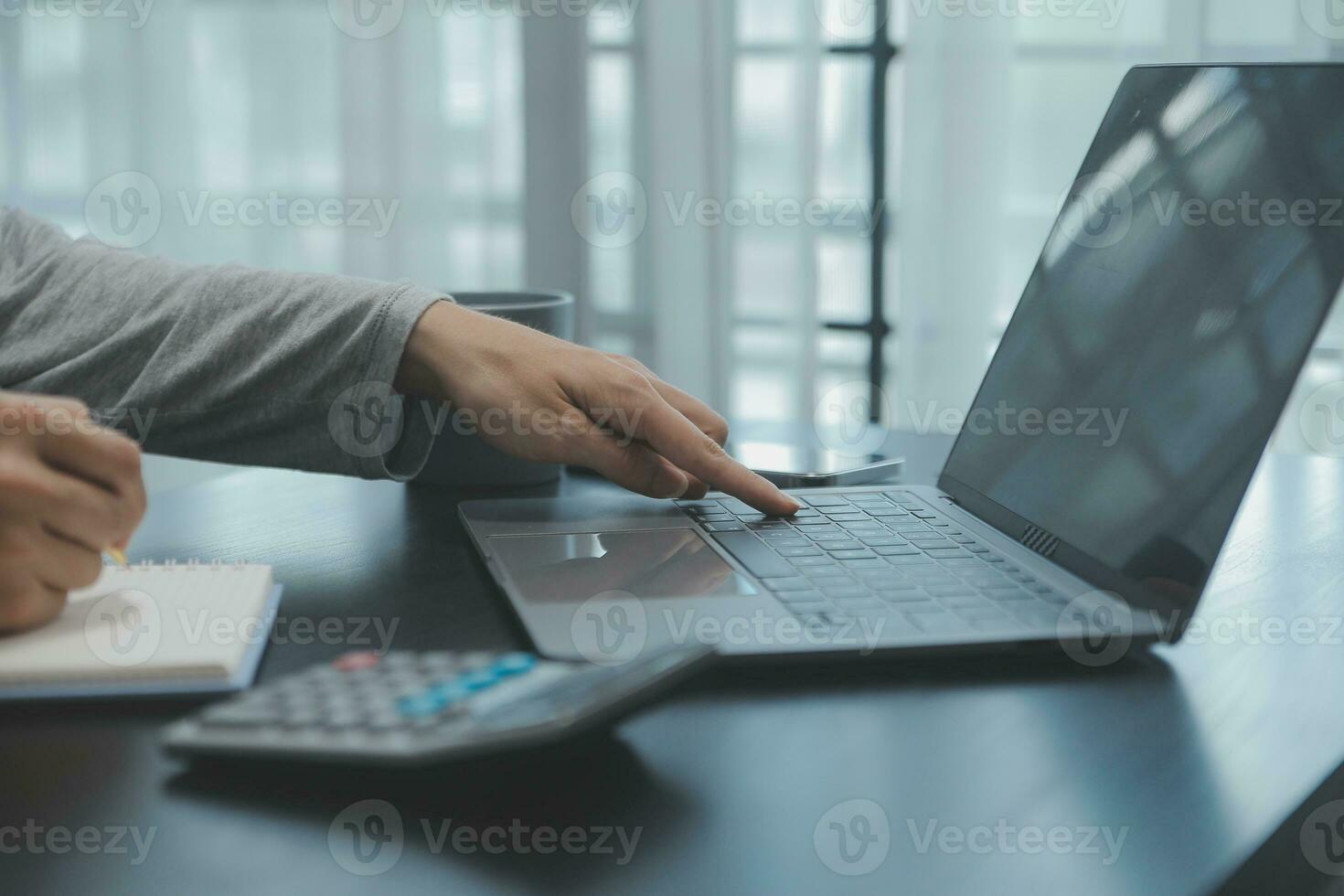 Asian Business woman using calculator and laptop for doing math finance on an office desk, tax, report, accounting, statistics, and analytical research concept photo