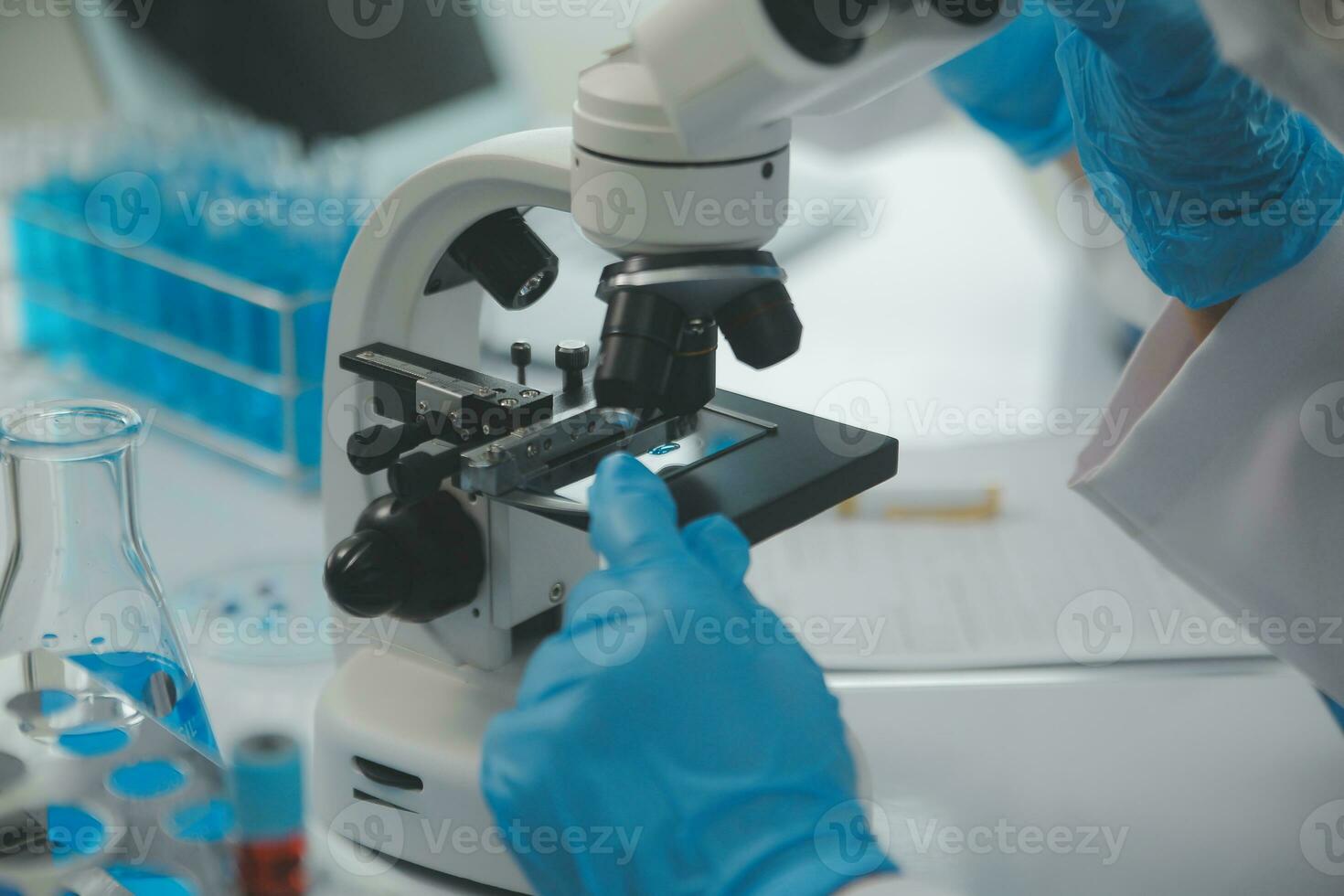Health care researchers working in life science laboratory. Young female research scientist and senior male supervisor preparing and analyzing microscope slides in research lab. photo