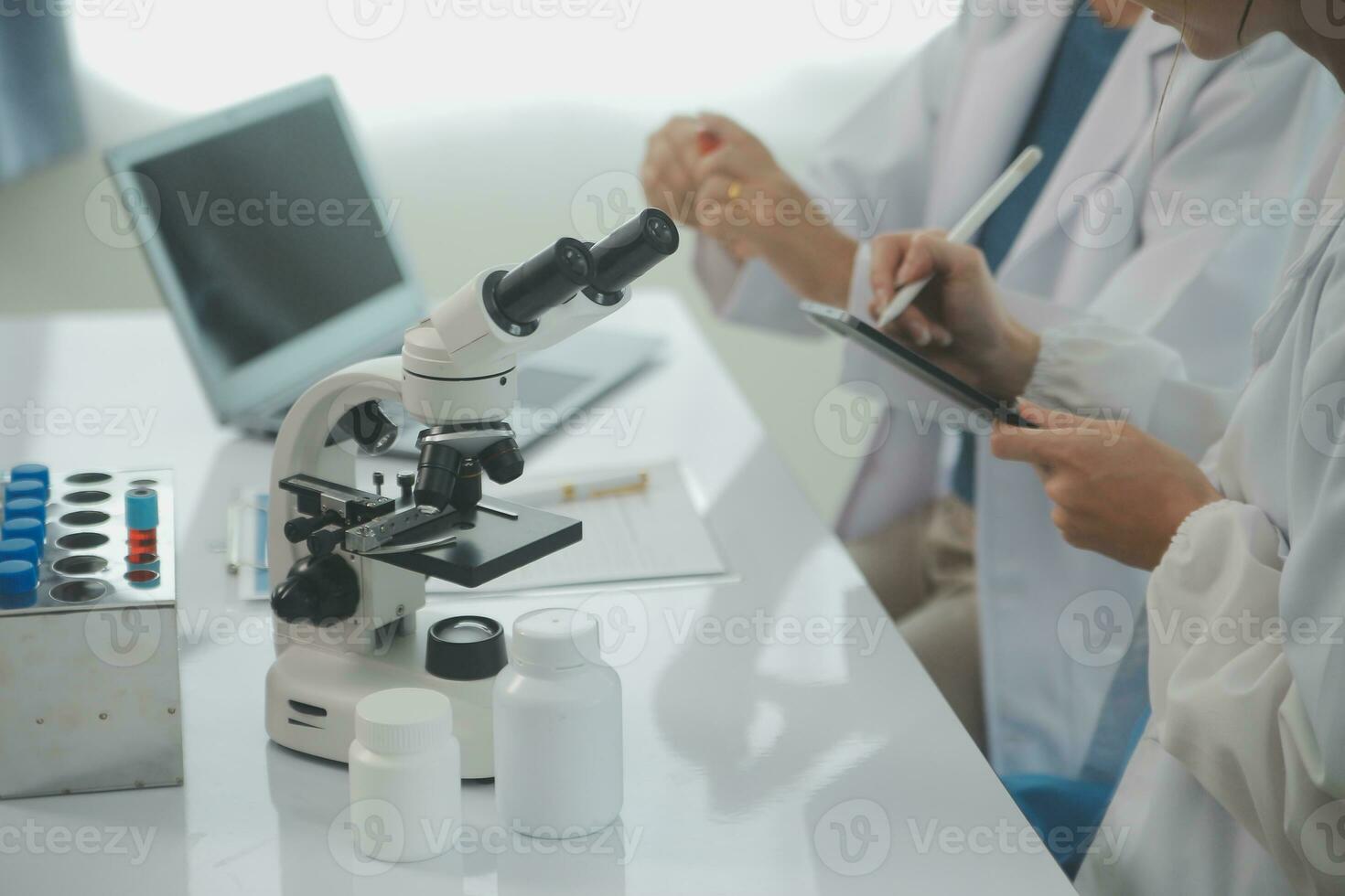 Health care researchers working in life science laboratory. Young female research scientist and senior male supervisor preparing and analyzing microscope slides in research lab. photo