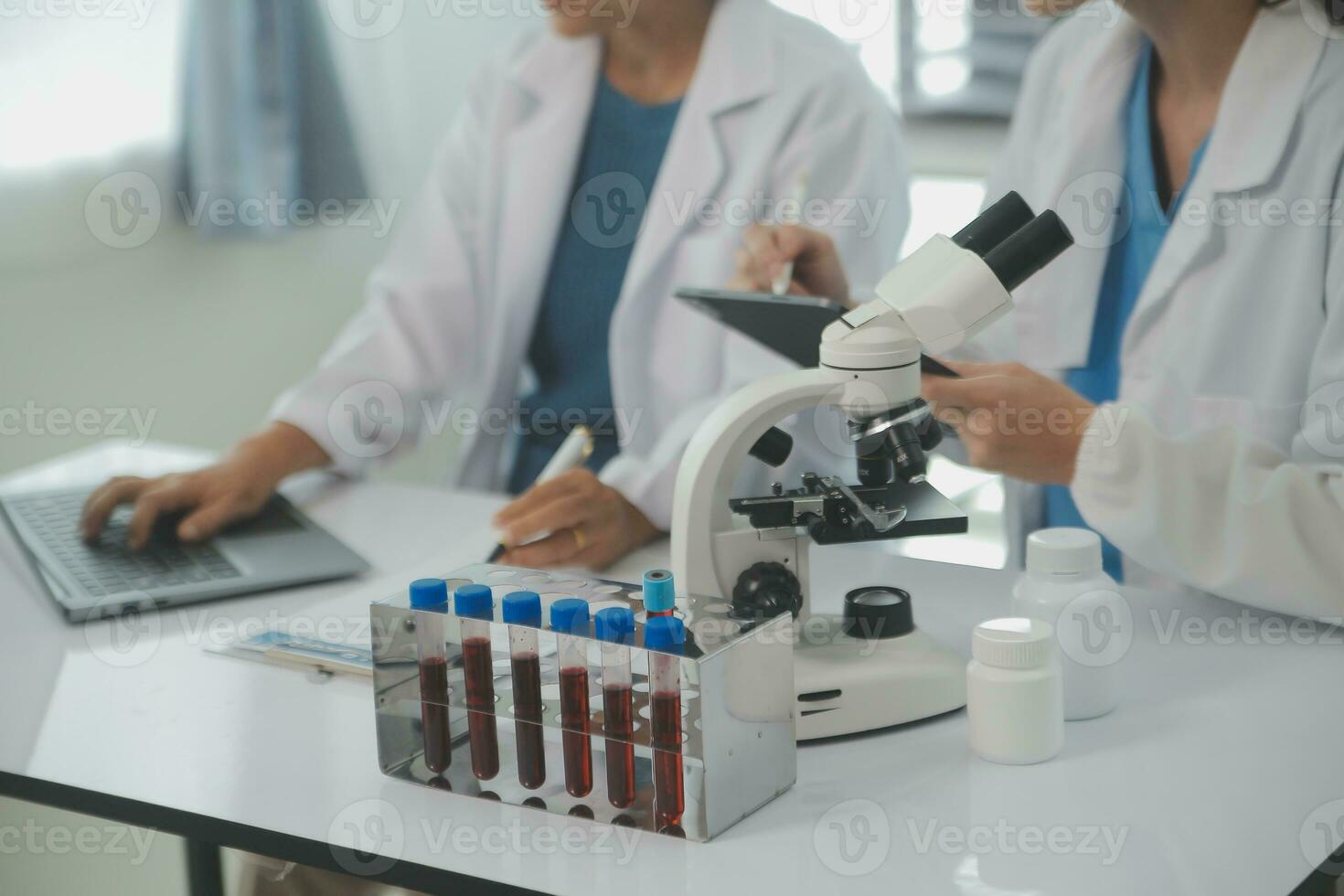 Health care researchers working in life science laboratory. Young female research scientist and senior male supervisor preparing and analyzing microscope slides in research lab. photo