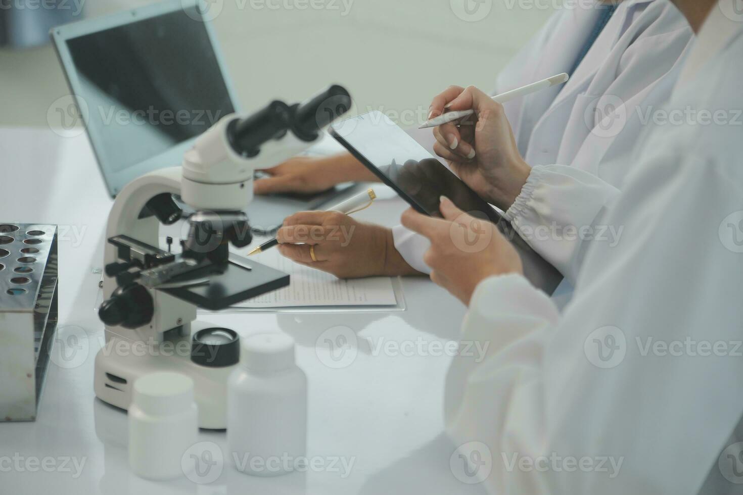 Health care researchers working in life science laboratory. Young female research scientist and senior male supervisor preparing and analyzing microscope slides in research lab. photo