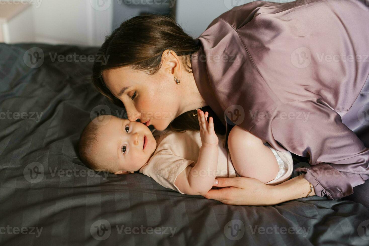 madre Besos su bebé en el cama foto