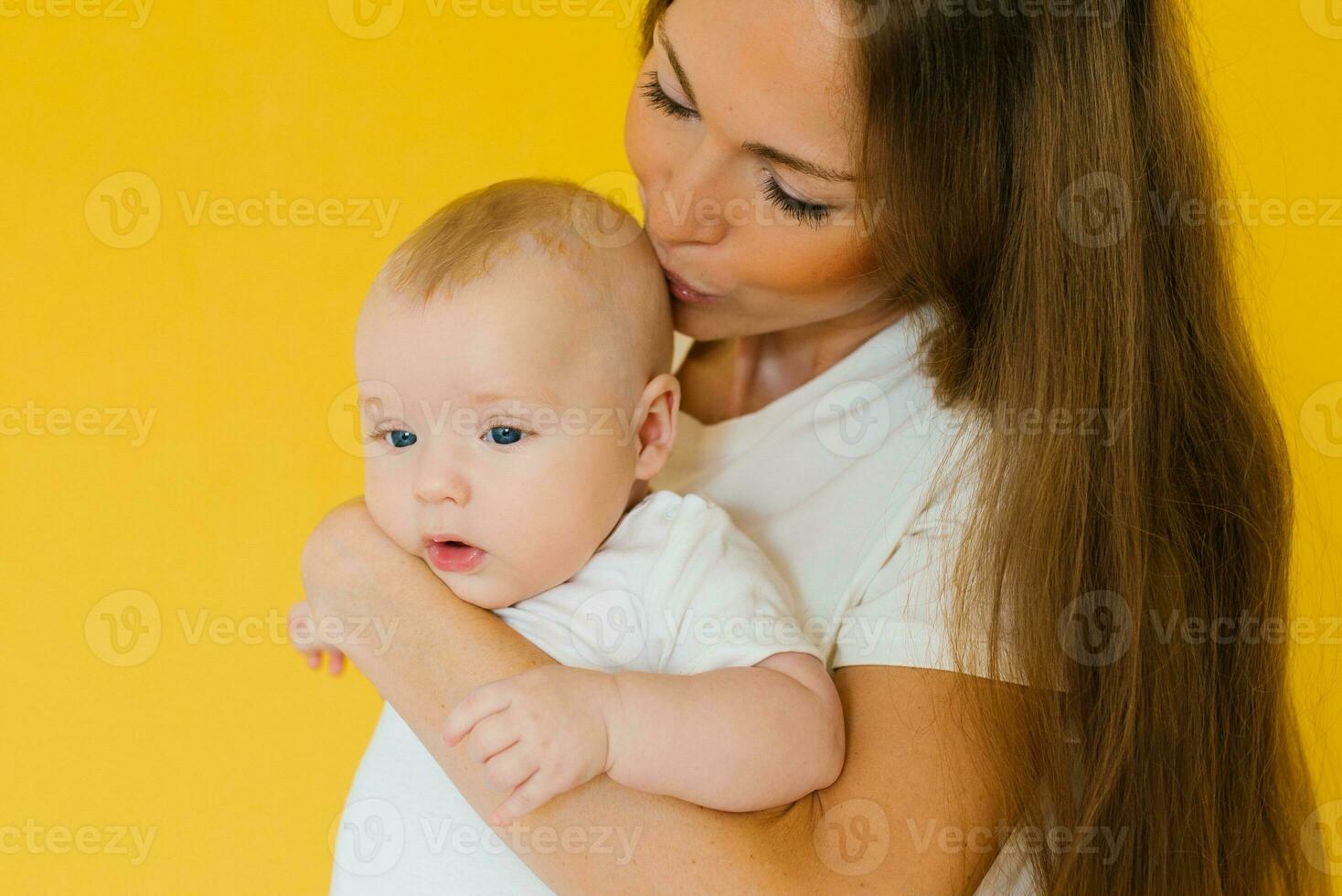 Loving mother takes care of a newborn baby, I think a portrait of a happy mother holding a sweet son in her arms and kissing him photo