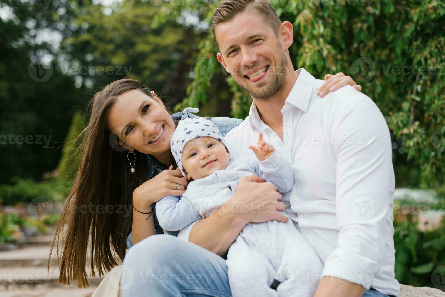 retrato de un alegre contento joven familia con un pequeño hijo descansando en el parque en primavera foto