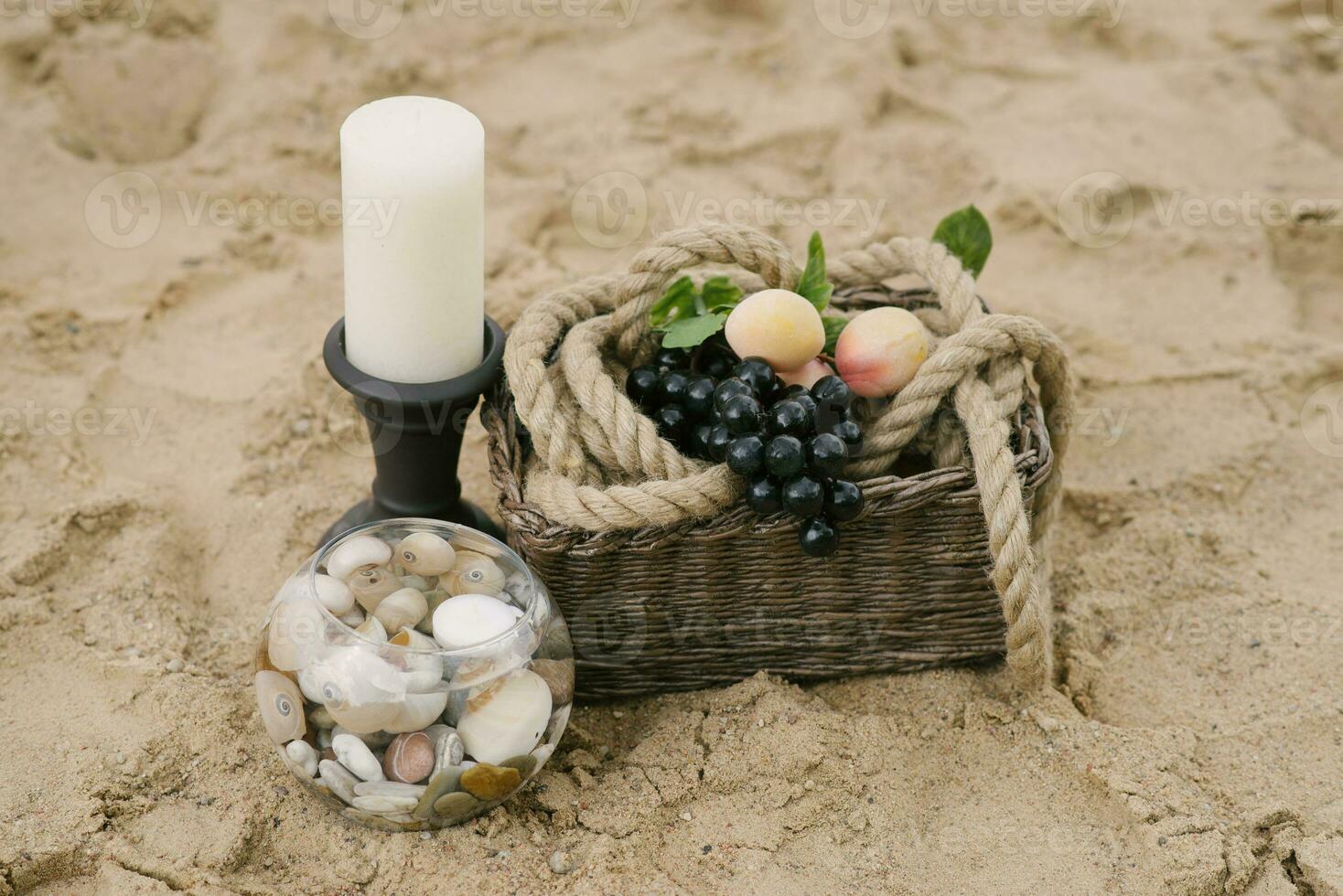 Fruits are in a basket, a candle, sea stones in a glass vase. Decor of a romantic dinner by the sea or ocean photo