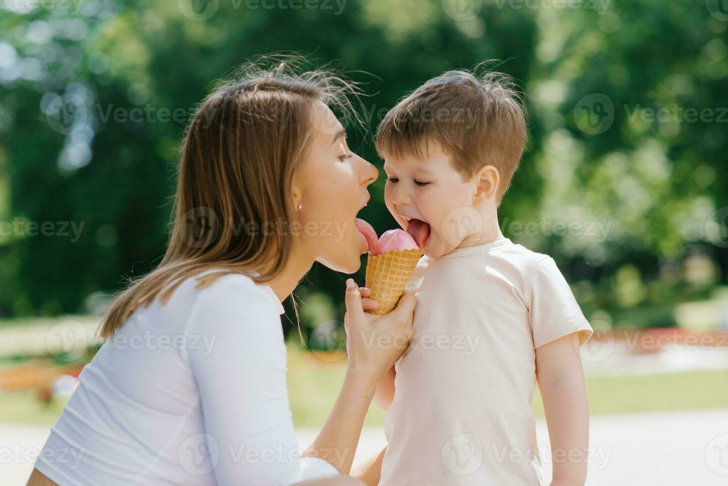 Young Caucasian mother with a little boy eating ice cream outdoors. Summer food and free time photo