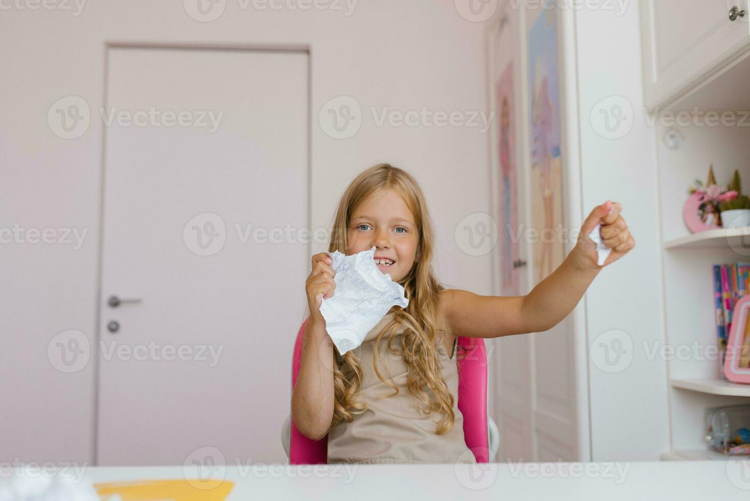 Happy schoolgirl tears up a sheet of a school notebook because of an incorrectly completed homework assignment photo