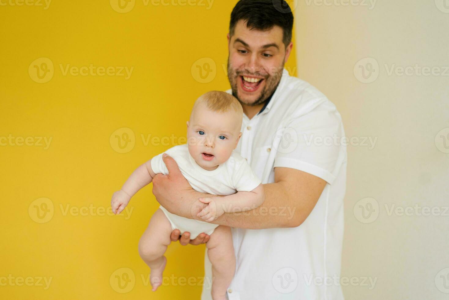 Positive cheerful dad holds his son in his arms. Happy parent and baby photo