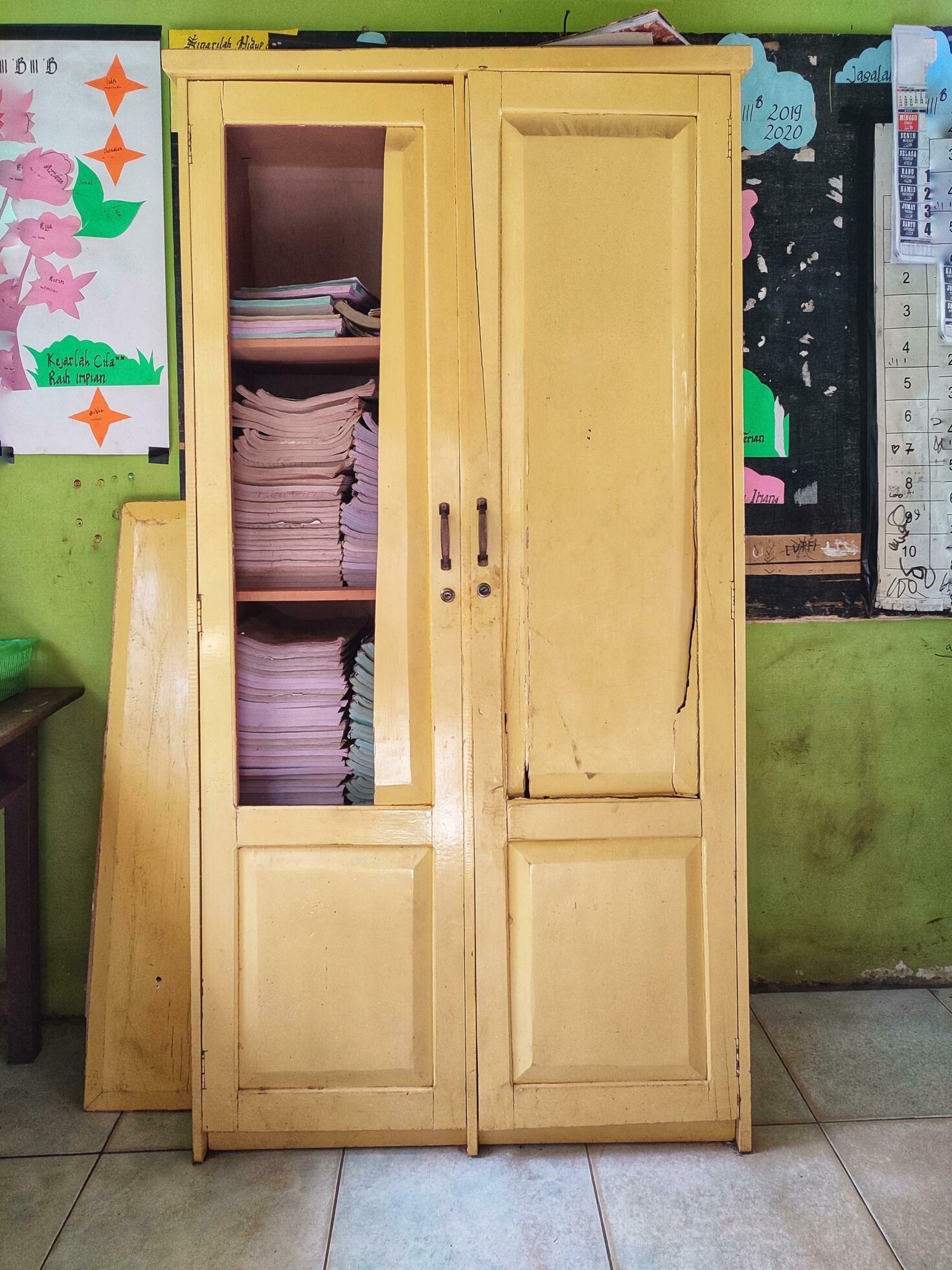 Broken cupboard with many books inside. Broken door at bookcase