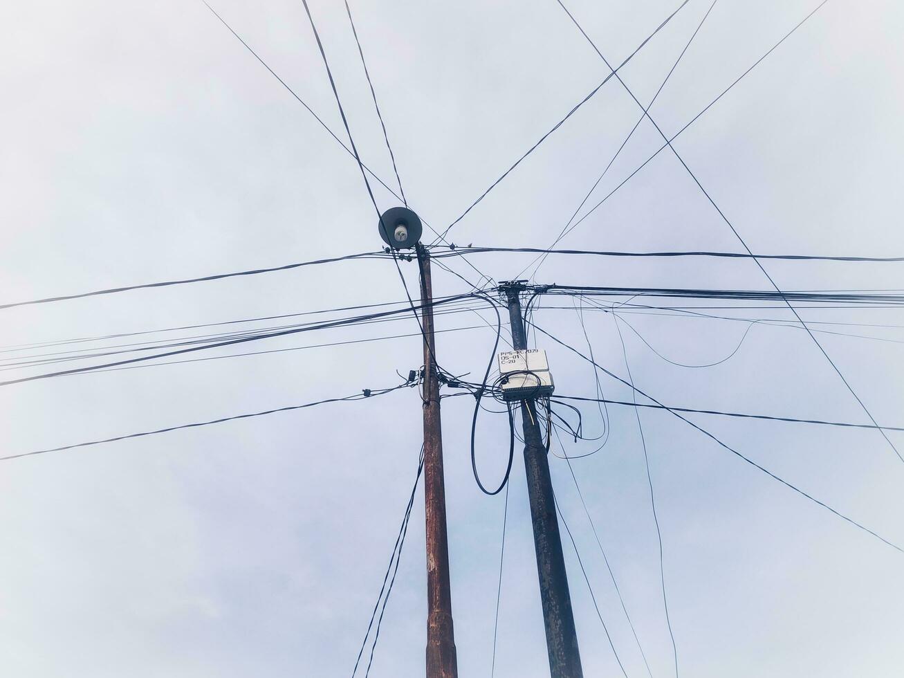 Electric poles with tangled wires with clouds background photo