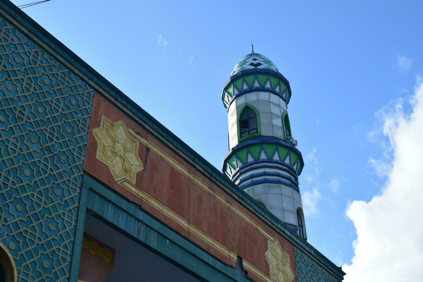 Ornamental minaret or tower of the mosque against blue sky photo