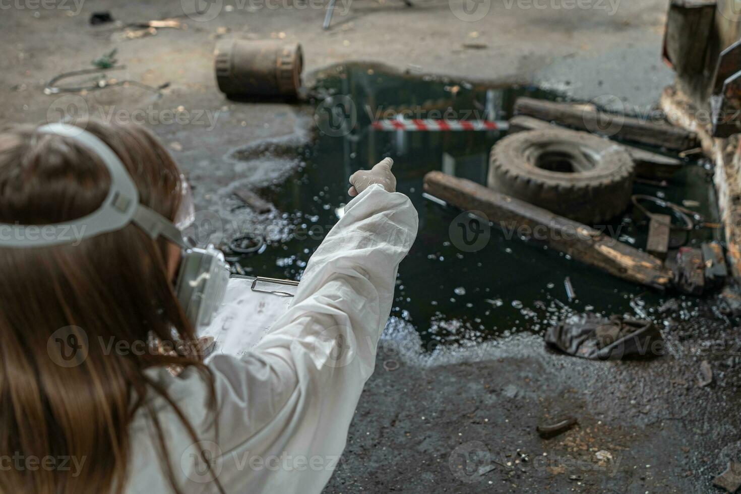 emergencia contaminación fábrica concepto. hembra químico vistiendo ppe y gas máscara inspeccionando petróleo en fábrica piso foto