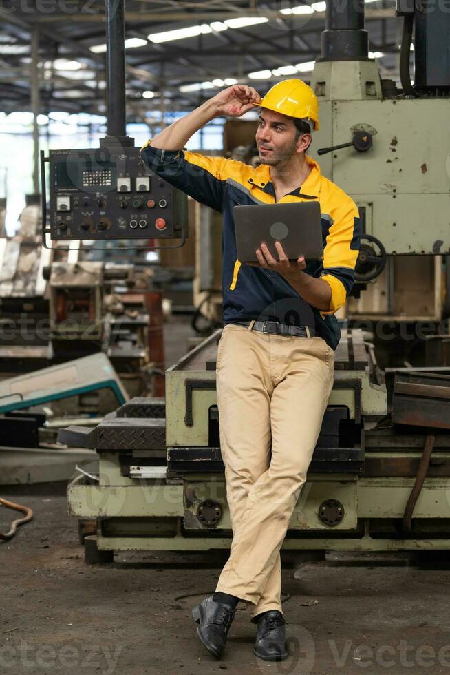 Caucasian engineer using a laptop in a factory. man working in plastics factory. photo