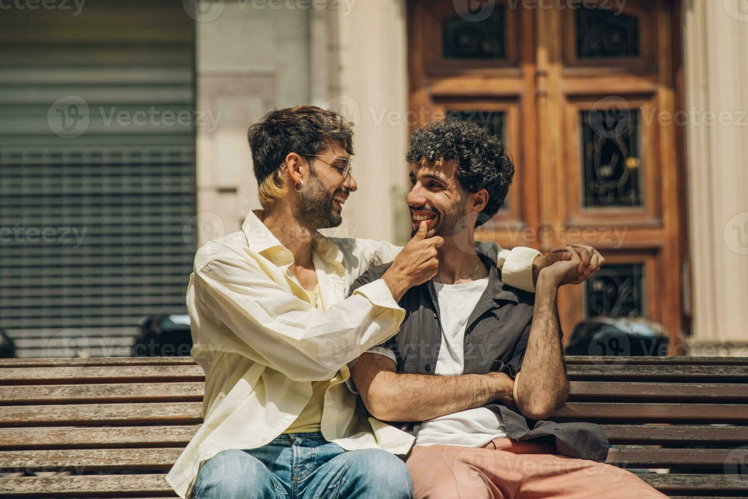 men sitting on a bench in the city kissing ang huging each other photo