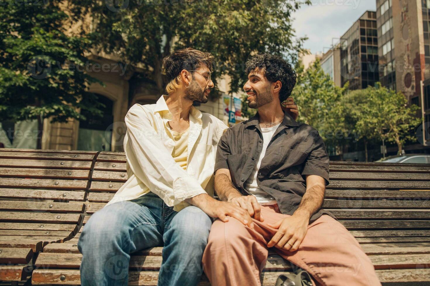 men sitting on a bench in the city kissing ang huging each other photo