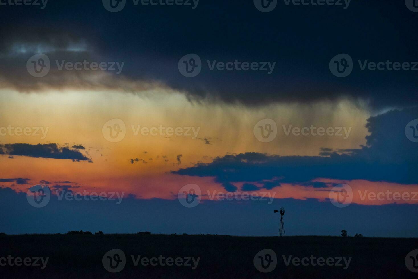 a windmill in a field with a cloudy sky photo