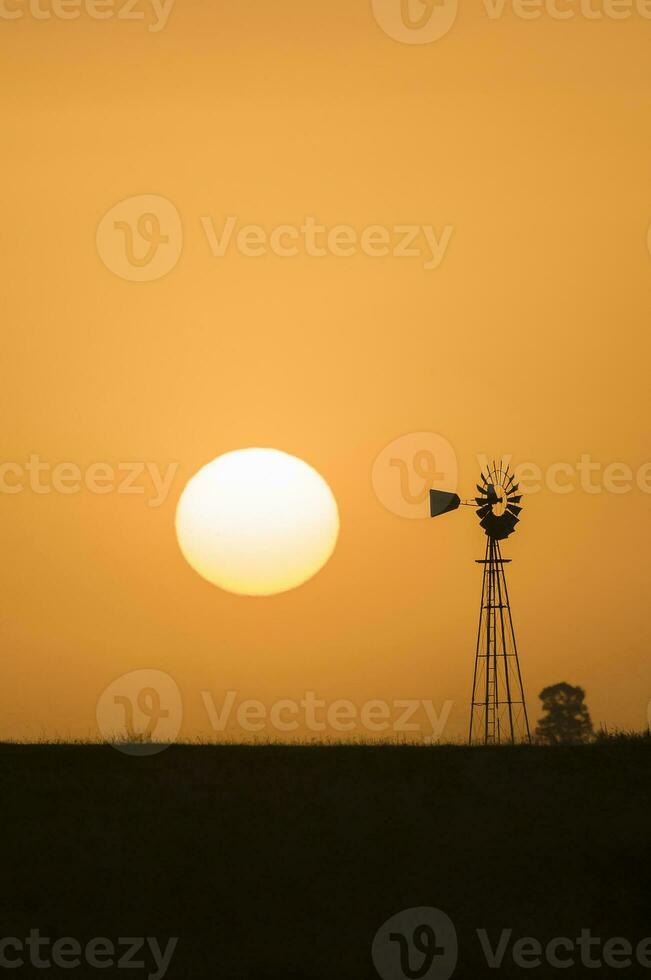 a windmill and a sun setting in the distance photo