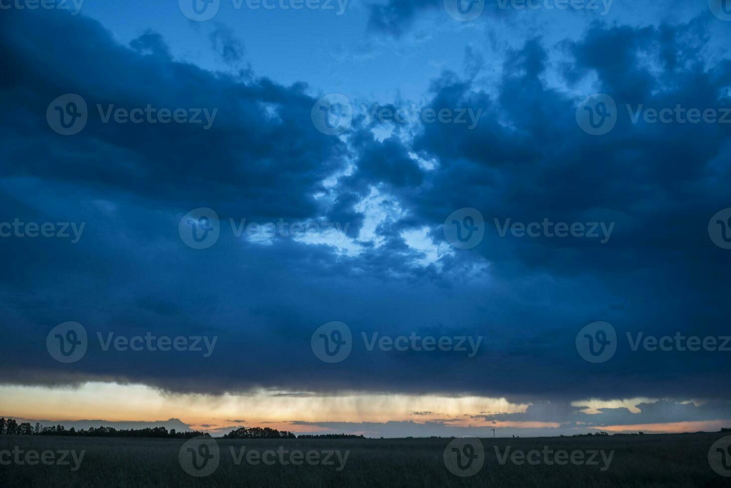 a dark sky with clouds over a field photo