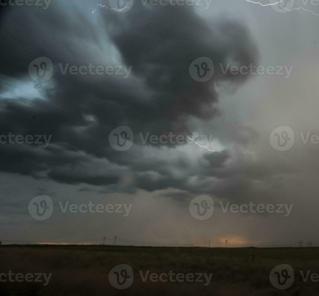 un Tormentoso cielo con relámpago y nubes terminado un campo foto