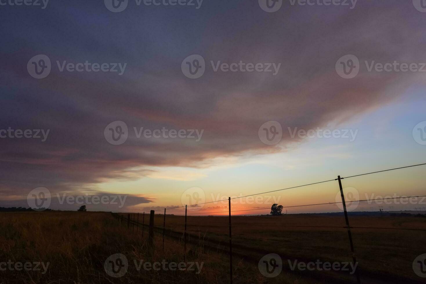 un puesta de sol terminado un campo con un cerca y un cerca enviar foto