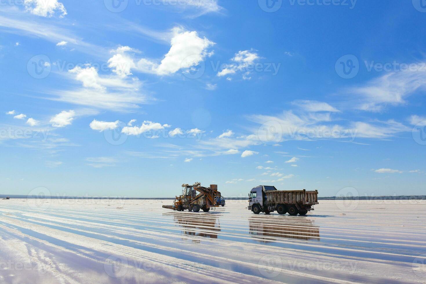 a large group of construction vehicles on a salt flat photo