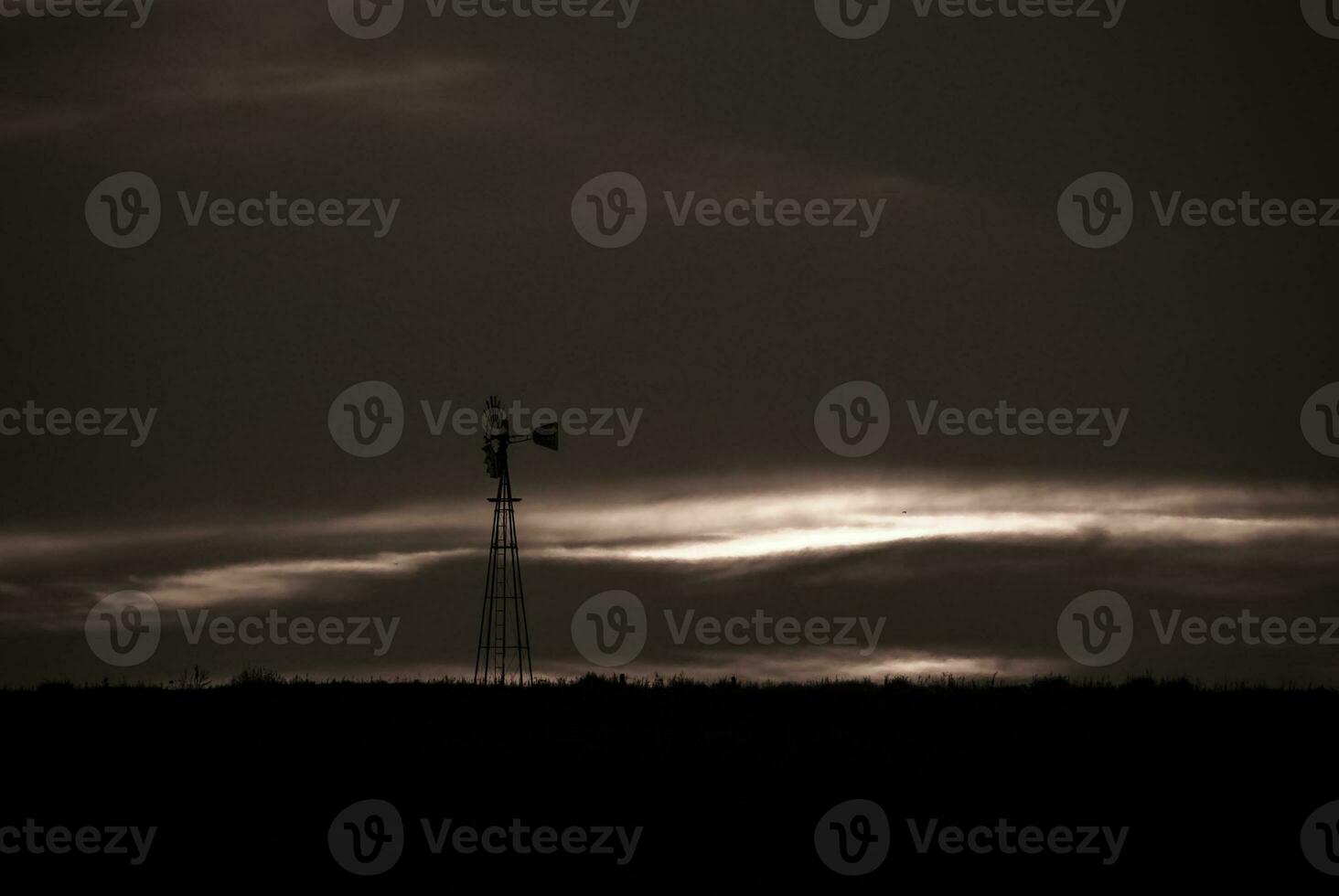 a windmill stands in the middle of a field photo