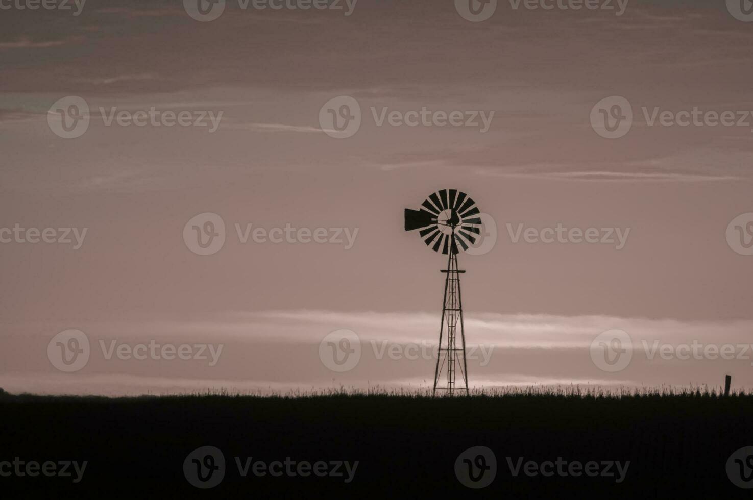 a windmill stands in the middle of a field photo