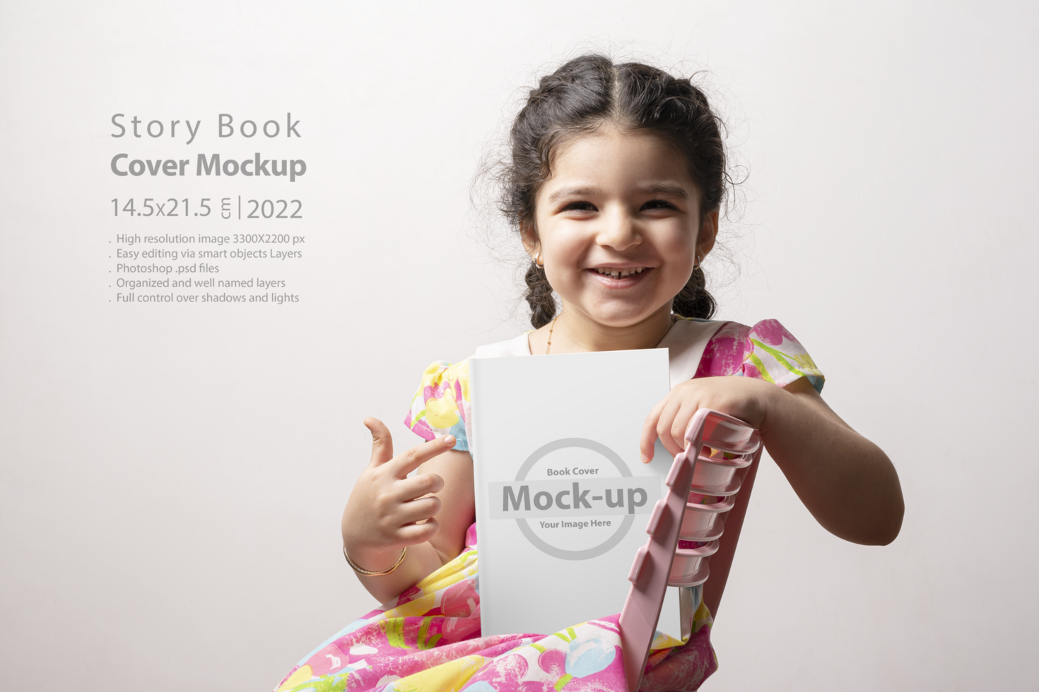 Happy little girl pointing to a story book with blank cover in front of her body psd