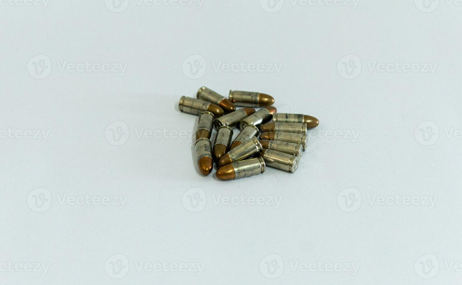 Pile of golden 9mm pistol bullets on a white background photo