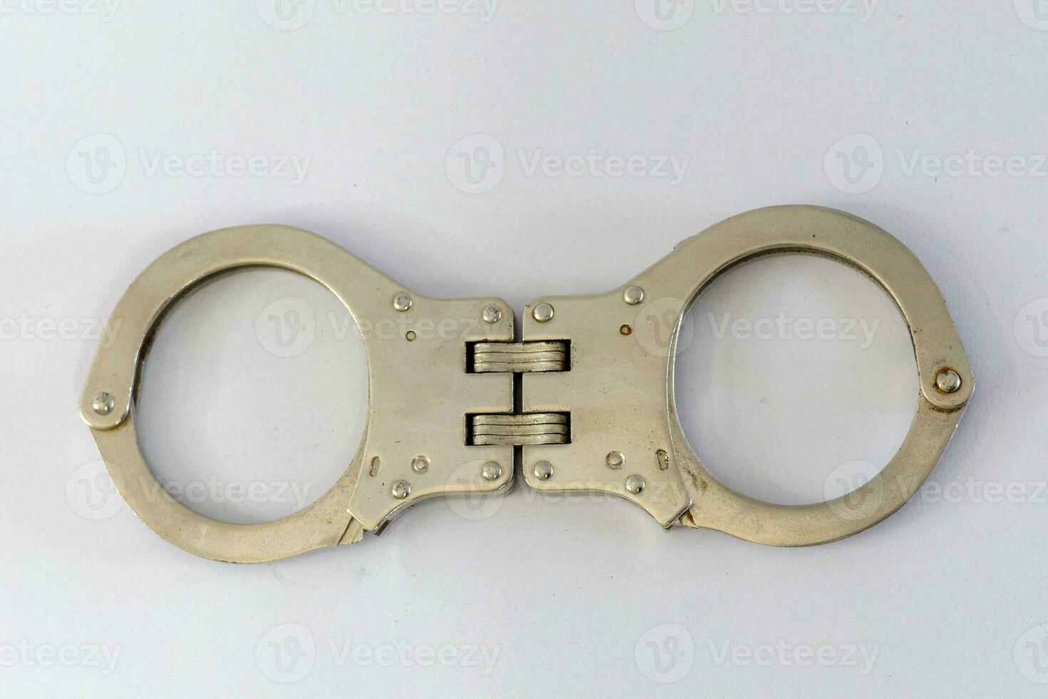 Pair of steel handcuffs isolated on white background. Silver metal handcuffs on white. photo