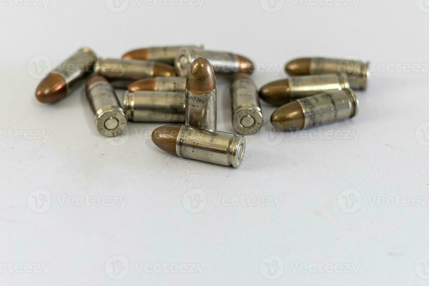 Pile of golden 9mm pistol bullets on a white background photo