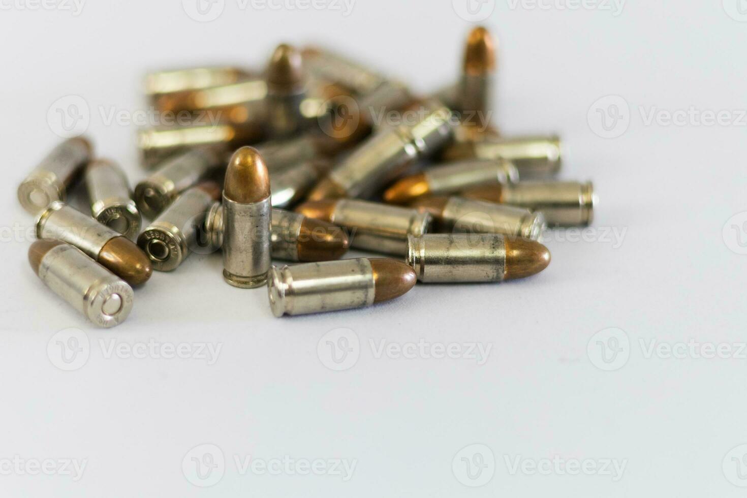 Pile of golden 9mm pistol bullets on a white background photo